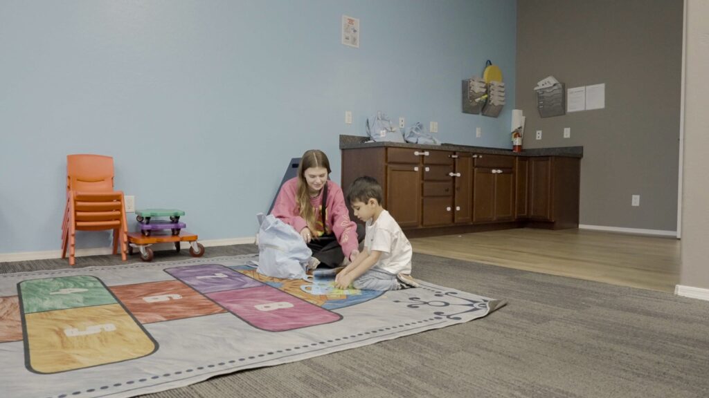 Treetop ABA therapist and child sitting on a colorful play mat during a session