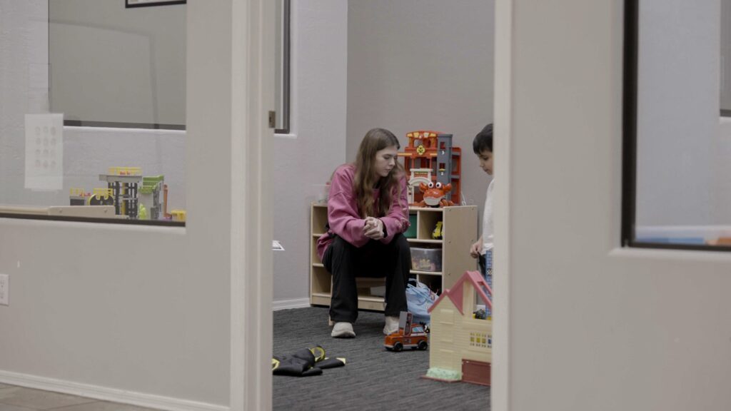 Therapist and child playing in a Treetop ABA therapy room seen through an observation window