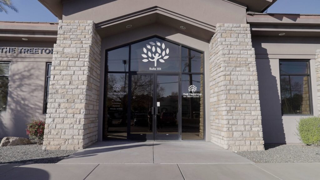 Full view of Treetop ABA Therapy Center entrance with branded glass doors and stone facade