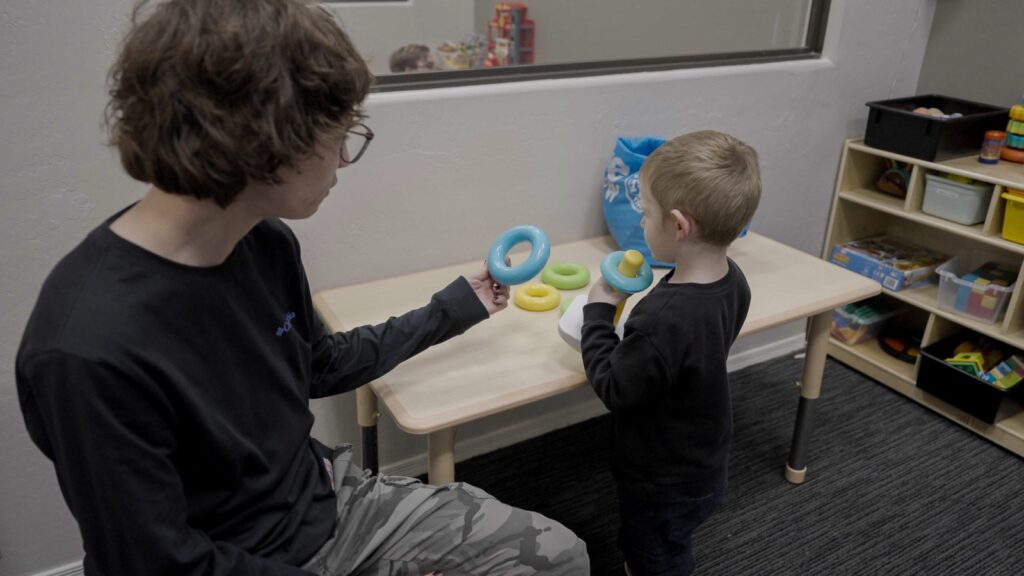 Treetop ABA therapist guiding a child through a ring stacking activity