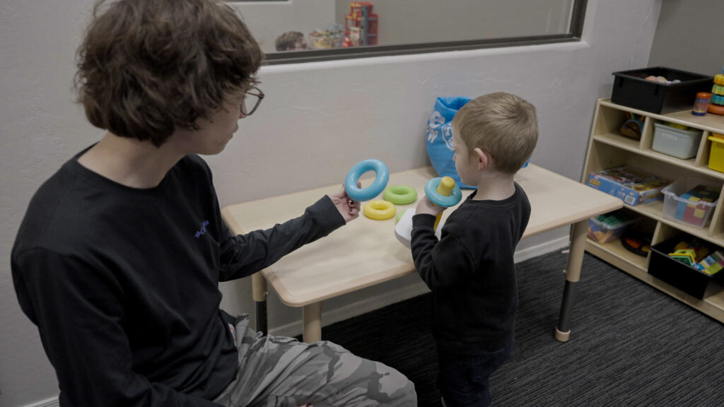 Treetop therapist working one-on-one with child on ring stacking activity