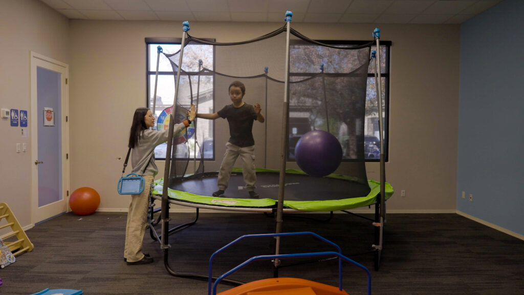Child on trampoline with Treetop ABA therapist during sensory activity