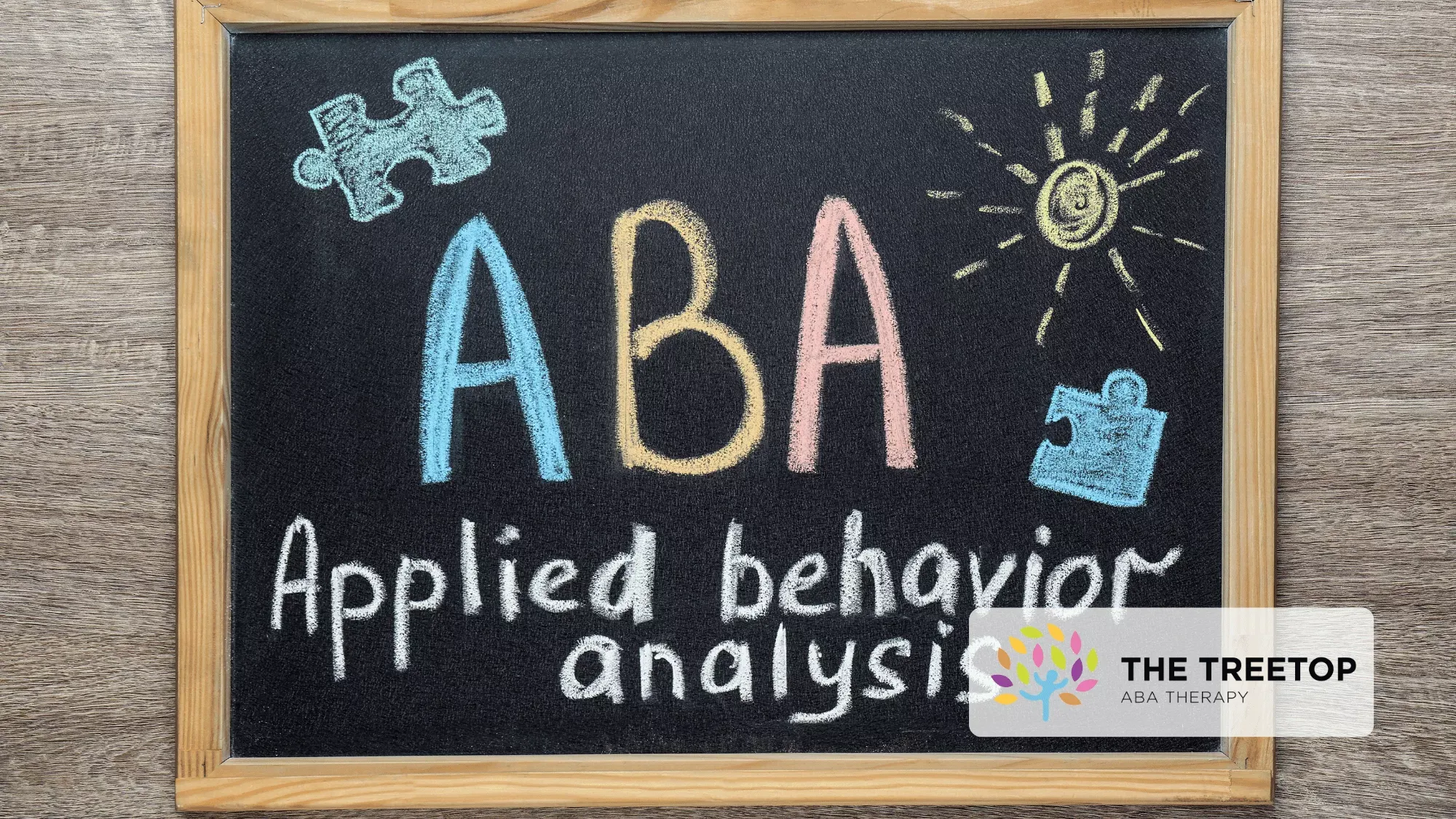 Chalkboard with the text "ABA Applied behavior analysis," decorated with colorful puzzle pieces and a sun drawing.