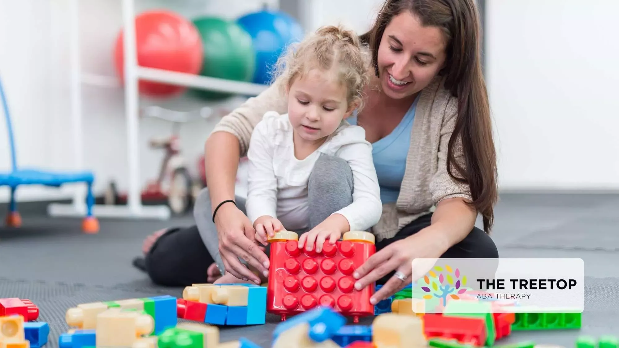 Woman helping child build a colorful block tower in a playroom