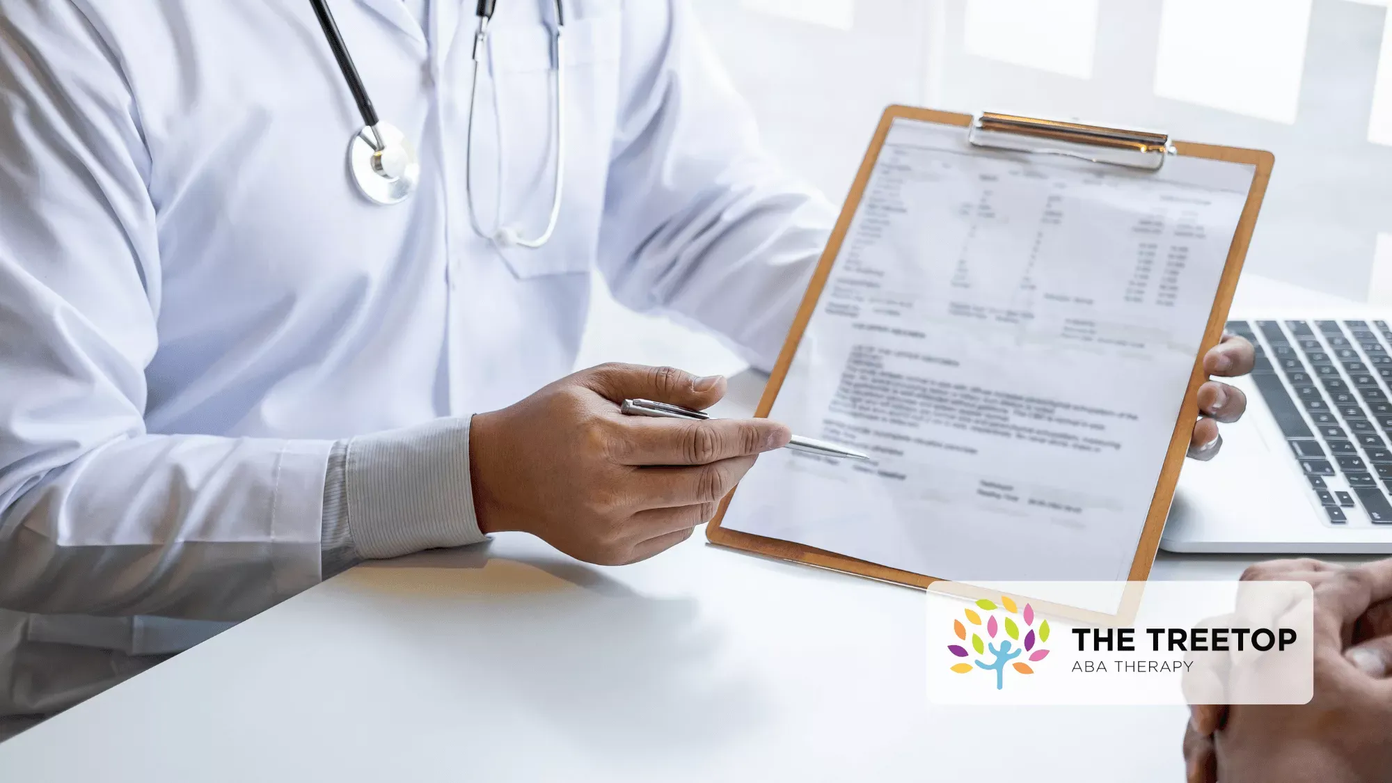 A healthcare professional in a white coat points to a document on a clipboard during a consultation.