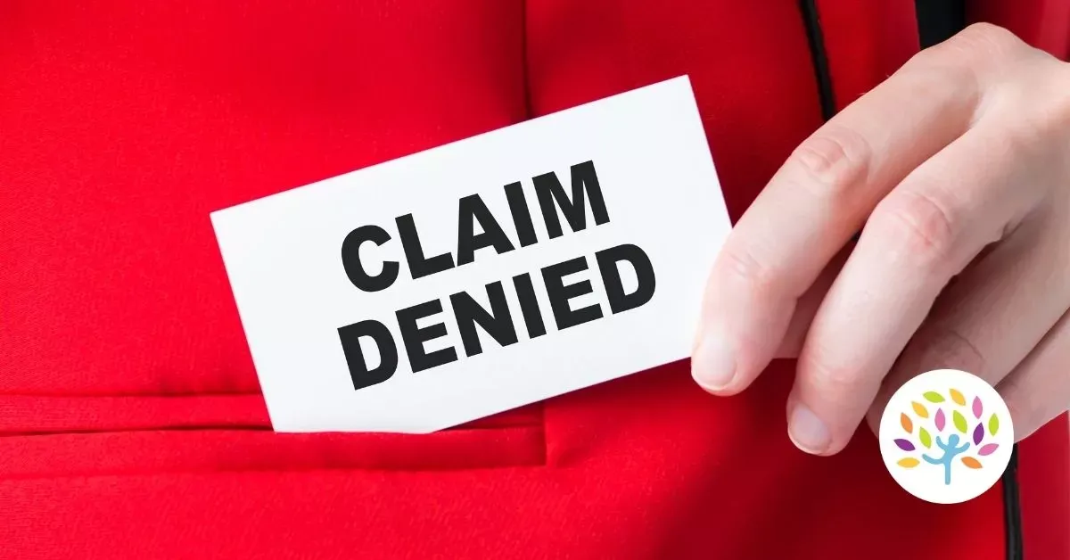 A hand holds a white card with the words "CLAIM DENIED" in bold black text against a red background.